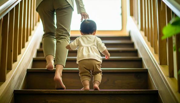 階段を下りるのが楽しい子供と支える母親の写真