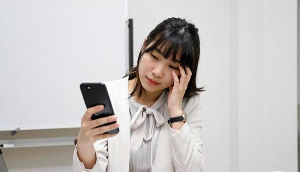 スマホ片手に思い悩む女性の写真