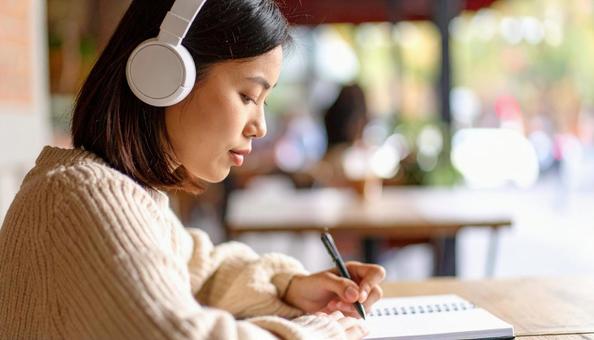 お気に入りの音楽を聴きながら勉強する女性 お気に入りの音楽を聴きながら勉強する女性の写真