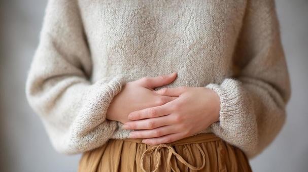 寒い日にお腹の冷えを感じる女性 寒い日にお腹の冷えを感じる女性の写真