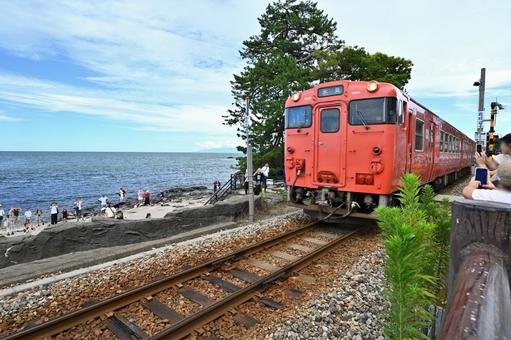 雨晴海岸を走るレトロな海沿い電車 雨晴海岸,立山連峰,氷見線の写真素材