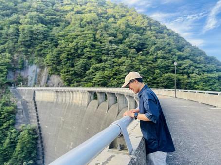 ダム 放流を眺める男性 ダム 放流を眺める男性の写真