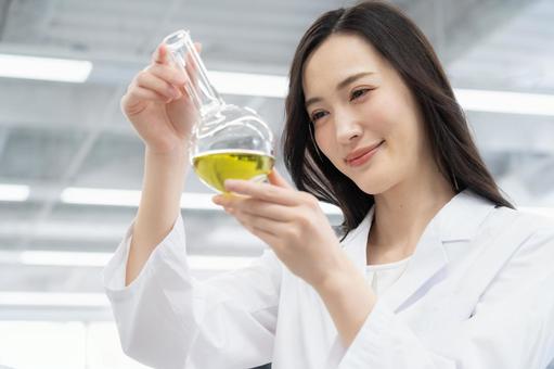 実験をする白衣の若い女性研究者 実験をする白衣の若い女性研究者の写真