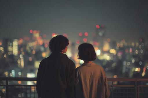 寄り添いながら夜景を見るカップル 寄り添いながら夜景を見るカップルの写真