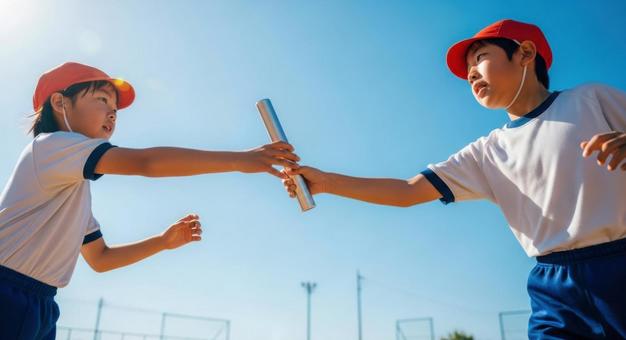 小学生が運動会リレーでバトンを渡す瞬間 小学生が運動会リレーでバトンを渡す瞬間の写真