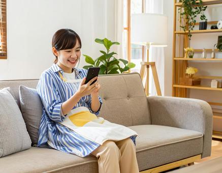 自宅でスマホを操作する女性 自宅でスマホを操作する女性の写真