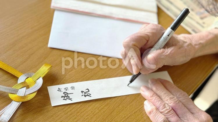 ご祝儀袋の別紙に名前を書く高齢女性の手元 ご祝儀袋,結婚式,お祝いの写真素材