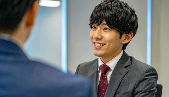 笑顔で話すスーツ姿の男性 笑顔で話すスーツ姿の男性の写真