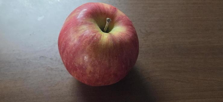 木目テーブルの上におかれたりんご 木目テーブルの上におかれたりんごの写真