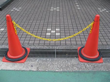 黄色いチェーンでつながれた三角コーン 三角コーン,赤,カラーコーンの写真素材