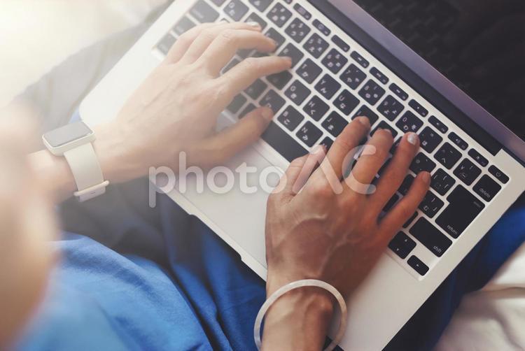 室内でベッドに座ってラップトップを使用する女性 パソコン,ラップトップ,ノートパソコンの写真素材
