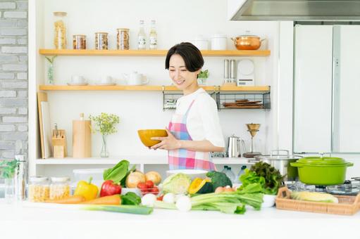 キッチンに立つエプロン姿のミドルの主婦 キッチンに立つエプロン姿のミドルの主婦 キッチン,野菜,エプロンの写真素材