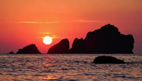 海の見える岩礁に沈む夕日 海の見える岩礁に沈む夕日の写真