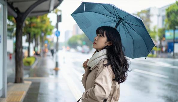 雨の中バス停でバスを待つ日本人女性 雨の中バス停でバスを待つ日本人女性の写真