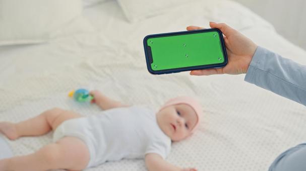 赤ちゃんを撮影する緑のスマホ画面 赤ちゃんを撮影する緑のスマホ画面の写真