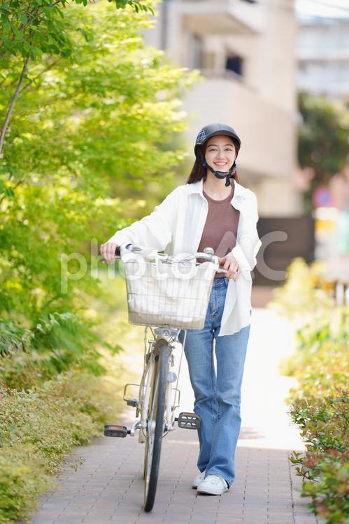自転車を押しながらヘルメットを被っている女性 女性,新緑,春の写真素材