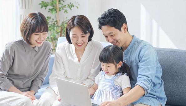 笑顔でパソコンをのぞき込む家族 笑顔でパソコンをのぞき込む家族の写真