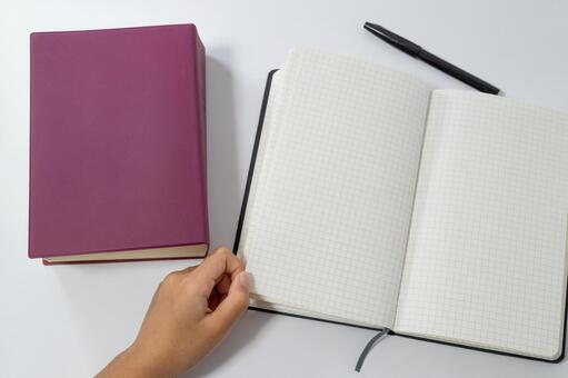 ノートを開く手と紫色のハードカバーの本 ノート,コピースペース,勉強の写真素材