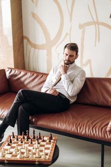 ソファで足を組んでチェスをしている男性 ソファで足を組んでチェスをしている男性の写真