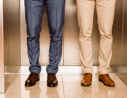 エレベーターに並ぶ二人の足元 エレベーターに並ぶ二人の足元の写真
