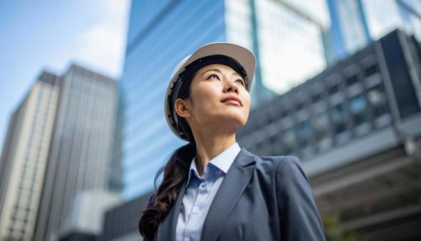 ビル背景にスーツにヘルメットの若い女性 ビル背景にスーツにヘルメットの若い女性の写真