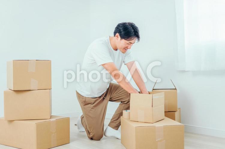 段ボールから洋服を出す男性 ダンボール,引越し,荷物の写真素材