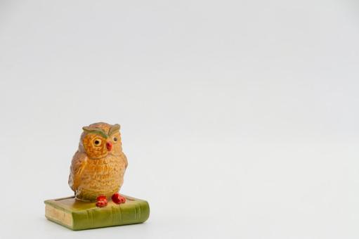 白背景に本と梟の置物の写真
