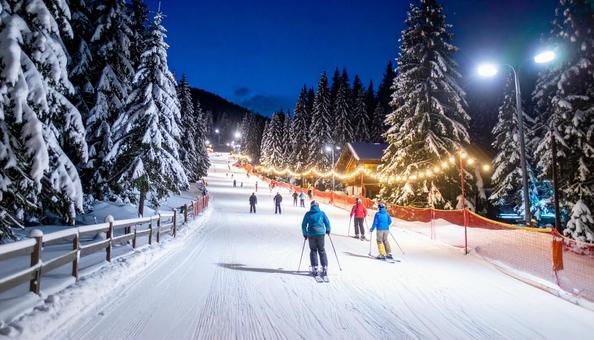 ライトアップされたスキー場で滑る人々の写真