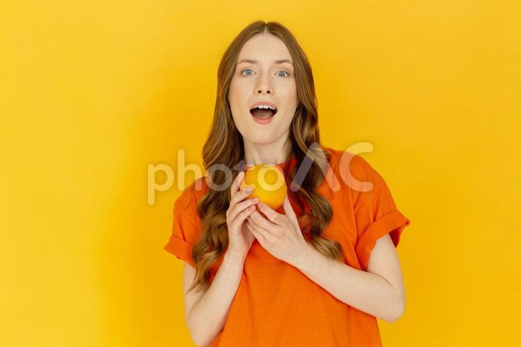 両手でオレンジを持ち話す女性 女性,オレンジ,外国人の写真素材