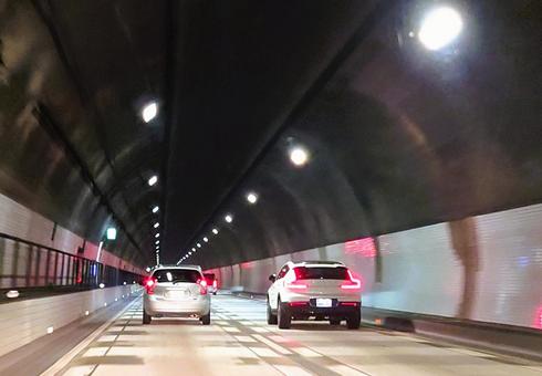 追い越しをかける車とトンネル内の歩道 追い越しをかける車とトンネル内の歩道の写真