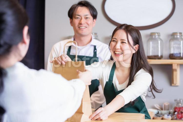 テイクアウト商品を渡す男女 テイクアウト,お持ち帰り,持ち帰りの写真素材