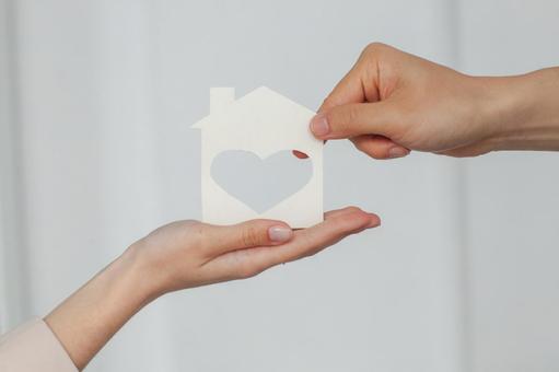 ハート型の家の切り抜きを渡す手元 保険業,事務職,接客業の写真素材