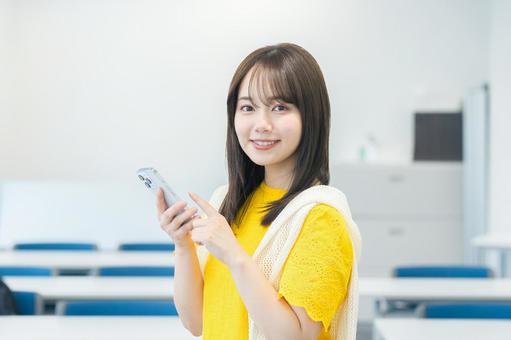教室でスマホを見る女子大学生 スマホ,笑顔,大学生の写真素材