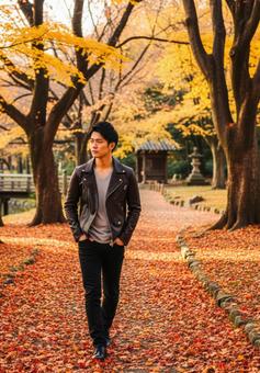 秋色に染まる公園で散歩するおしゃれな男性 秋色に染まる公園で散歩するおしゃれな男性の写真