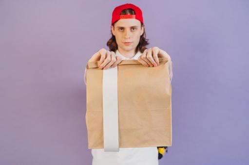 紙袋を持つフードデリバリーの男性（紫背景） 配達,フードデリバリー,デリバリーの写真素材