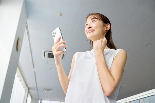 ジムでガッツポーズする女性　スマホを使う スポーツジム,ガッツポーズ,スマホの写真素材