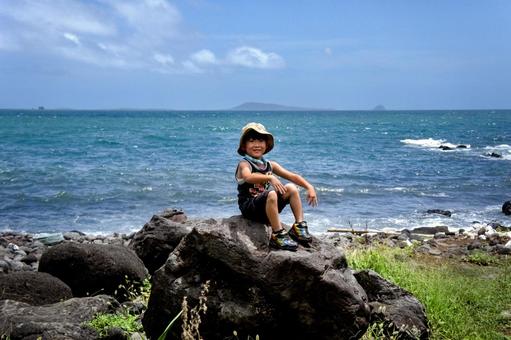 ＜素材＞夏の海岸の岩の上に座る男の子 子供,笑顔,海の写真素材