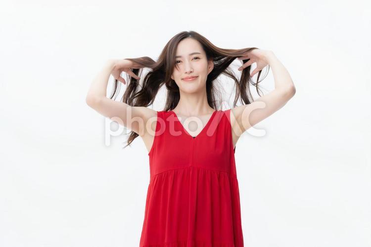 ヘアケアをする白バックの若い女性 ヘアケア,ビューティー,女性の写真素材