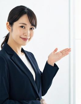 案内ポーズをするスーツ姿の女性 案内ポーズをするスーツ姿の女性の写真