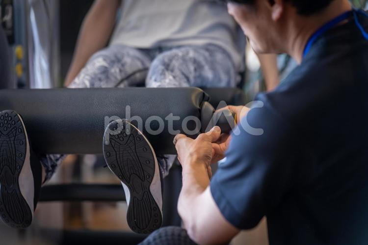 スポーツジムで脚を鍛える女性（顔なし） スポーツジム,レッグプレス,レッグエクステンションの写真素材