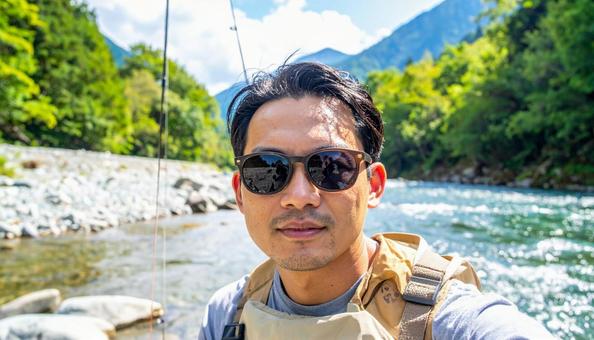 サングラスをして渓流釣りをする男性 サングラスをして渓流釣りをする男性の写真