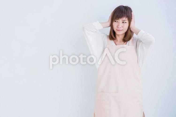 耳をおさえるエプロン姿の女性 うるさい,女性,エプロンの写真素材