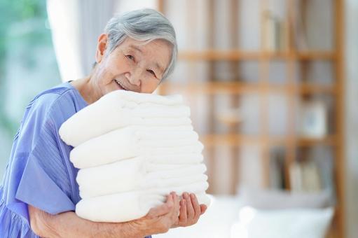 白いタオルを運ぶおばあちゃん 女性,タオル,持つの写真素材