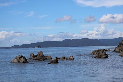 岩と青い海と対岸の山と雲と青空の風景 岩と青い海と対岸の山と雲と青空の風景の写真