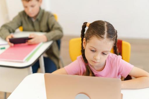 パソコンを見る女の子と携帯を見る男の子 男の子,女の子,子どもの写真素材