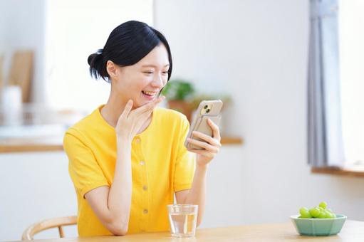 顎に手を当てスマホを見て笑う女性 女性,スマートフォン,持つの写真素材