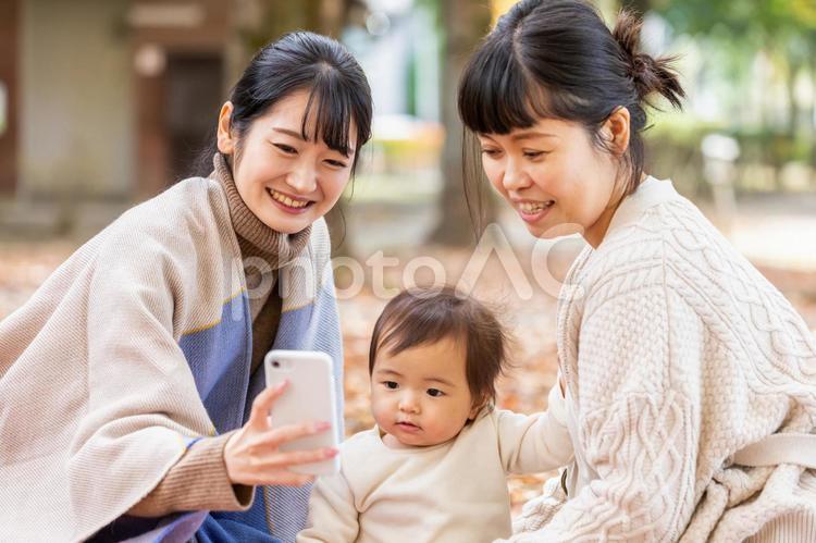 公園でスマホを見ながらママ友と話す女性 ママ友,スマホ,見るの写真素材