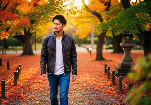 秋色に染まる公園で散歩するおしゃれな男性 秋色に染まる公園で散歩するおしゃれな男性の写真
