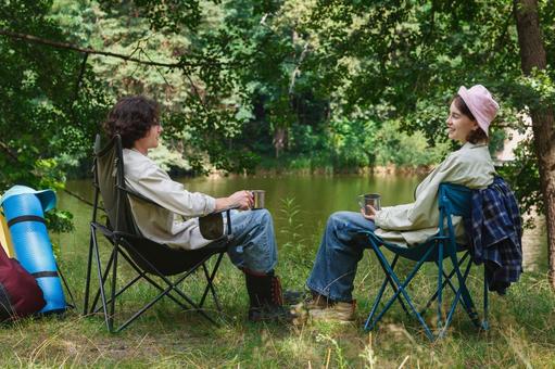 黒い椅子に座る二人のキャンパー 男女,外国人,キャンプの写真素材