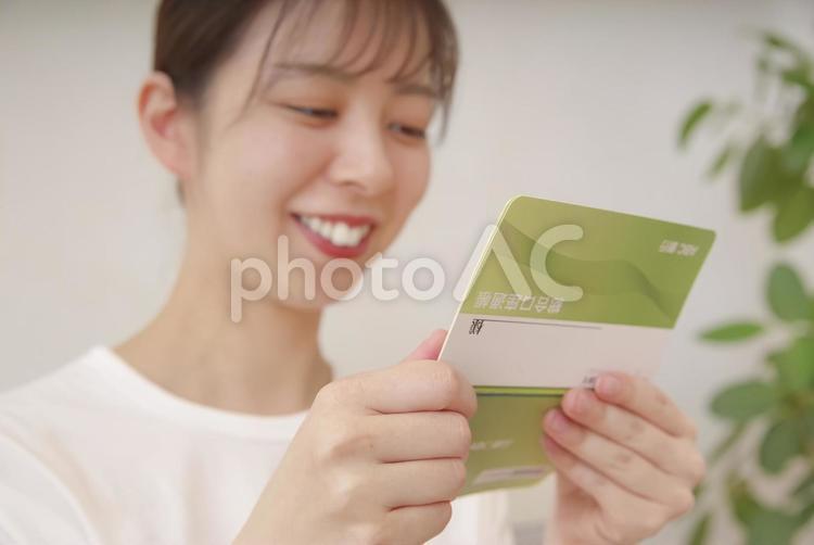 通帳を見てほほえむ女性 女性,微笑む,微笑みの写真素材